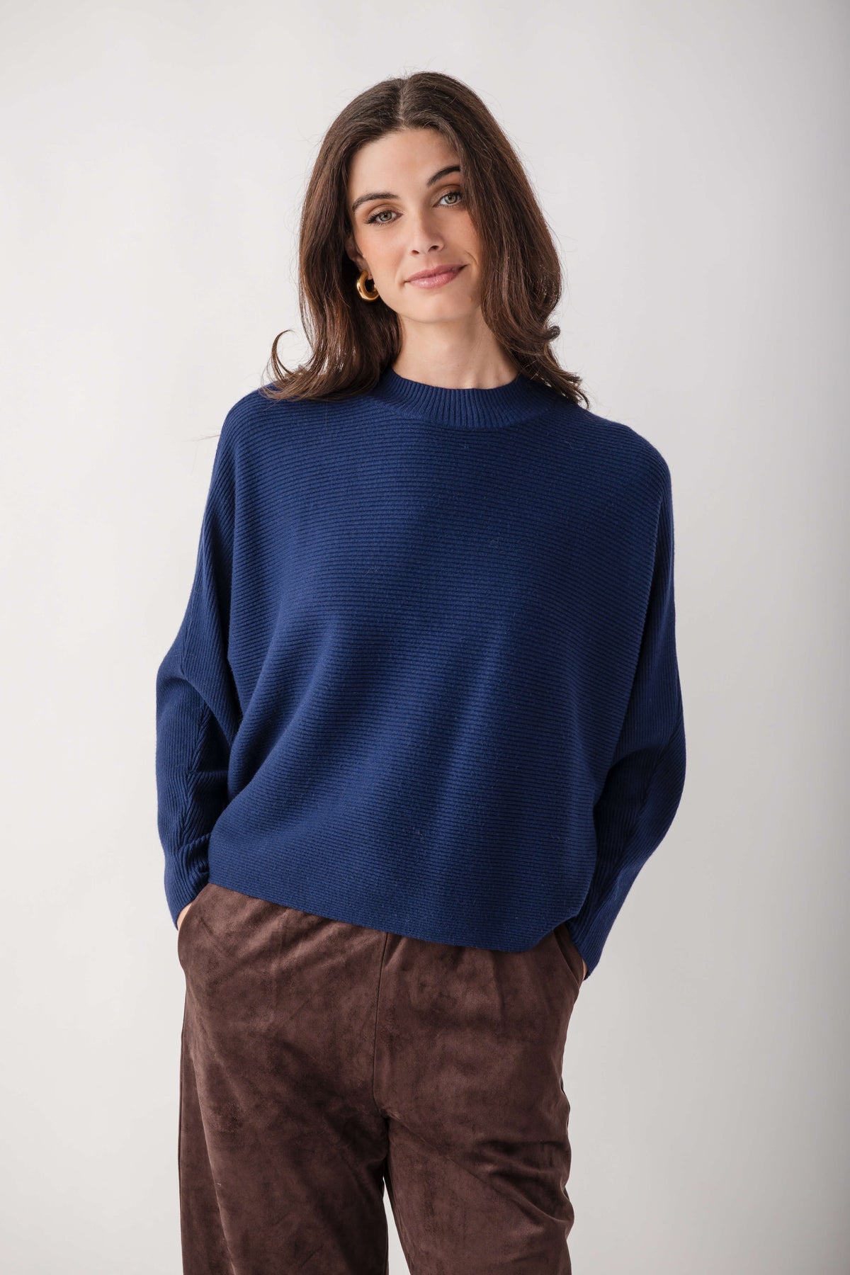 Navy blue crewneck sweater with dolman sleeves and ribbed texture, worn with brown pants.