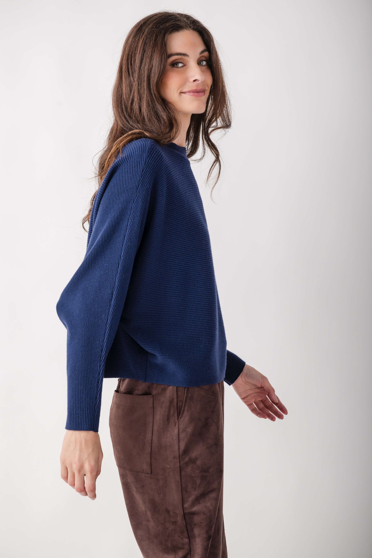 Navy ribbed crewneck sweater with dolman sleeves on model wearing brown pants.