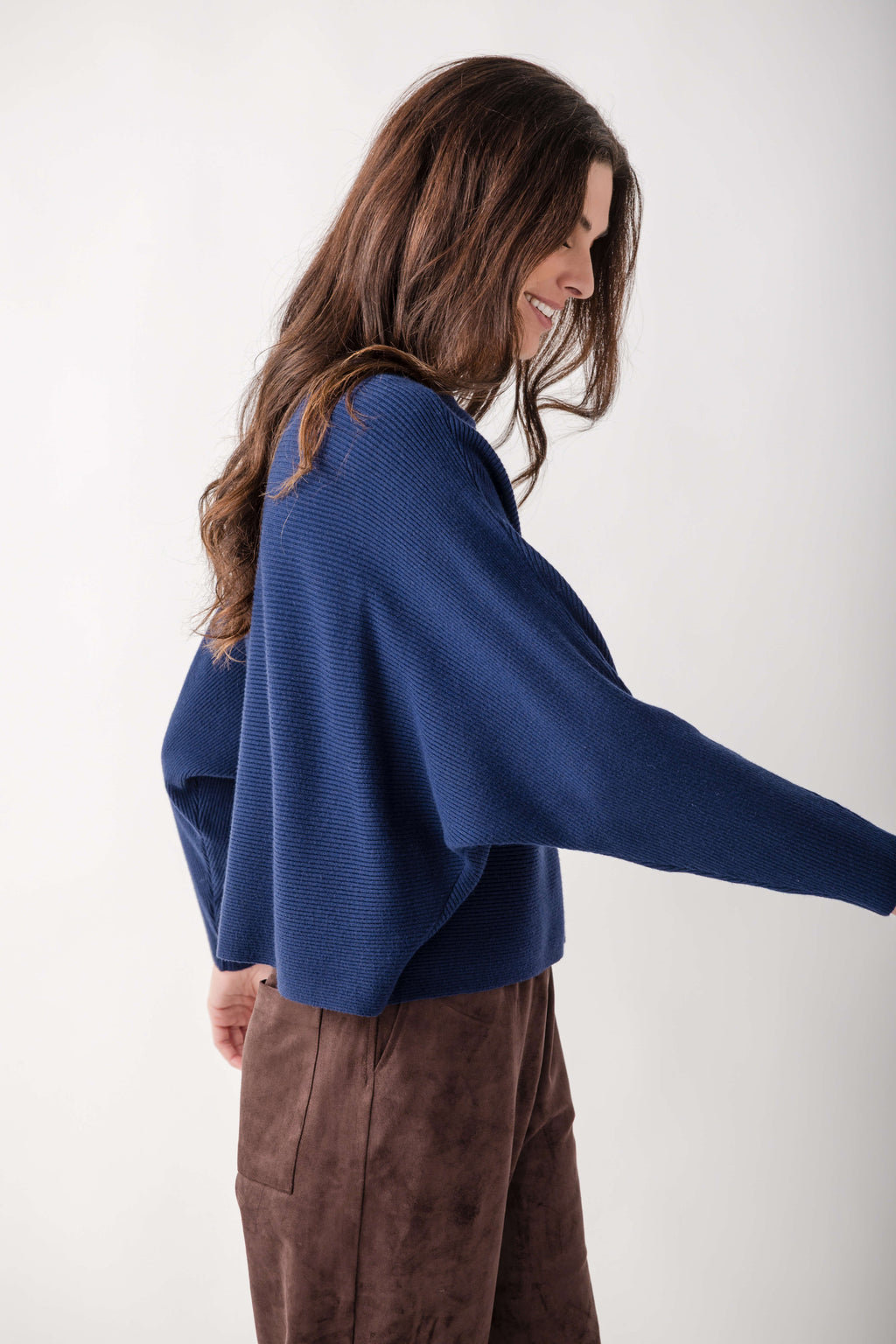 Navy blue crewneck sweater with dolman sleeves and textured knit fabric on model wearing brown pants.