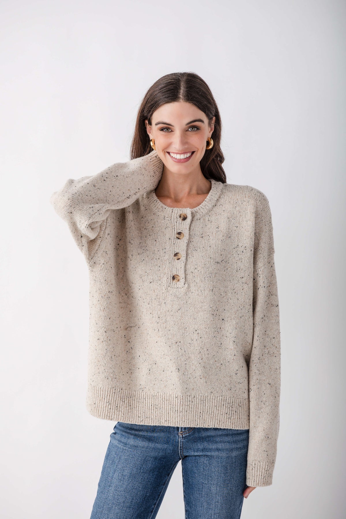 Heather beige Henley sweater with button front and speckled knit texture, worn with blue jeans.