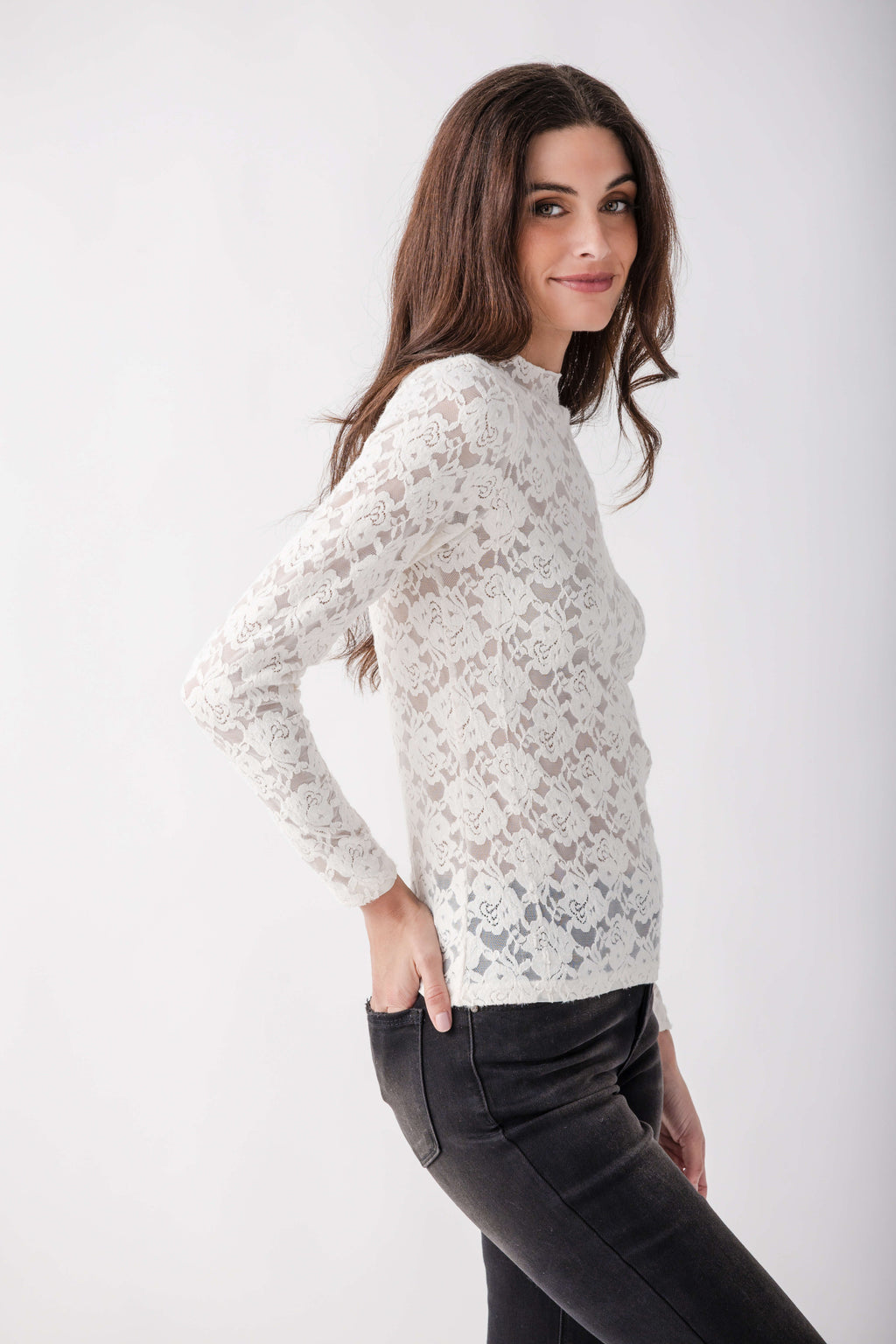 White lace long-sleeve mockneck top with patterned texture worn with black pants.