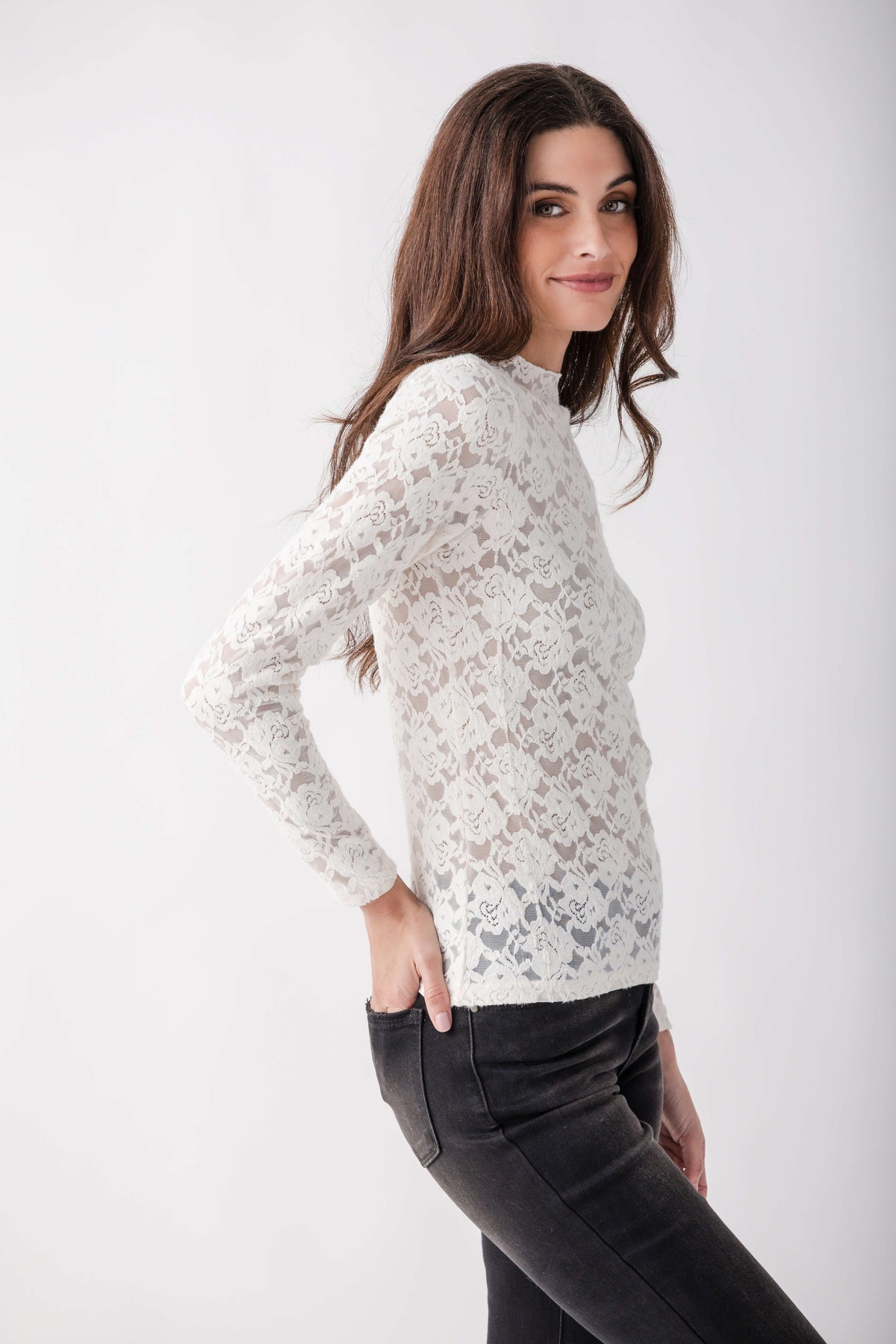 White lace long-sleeve mockneck top with patterned texture worn with black pants.