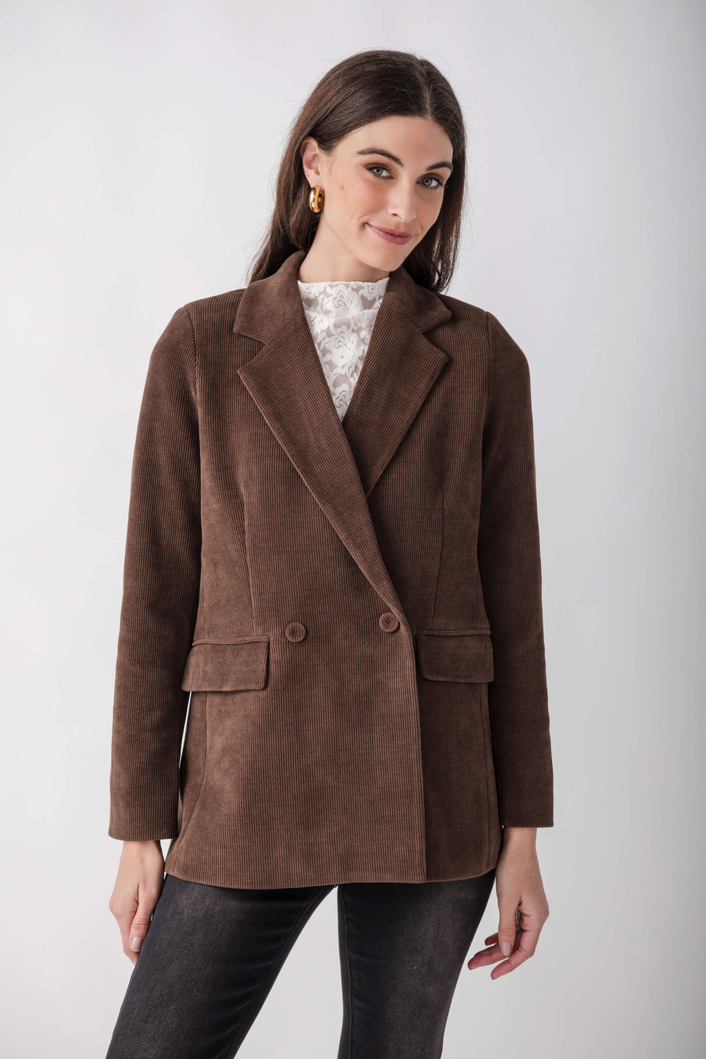 Brown corduroy double-breasted blazer with notch lapels, worn over a white lace top and dark jeans.