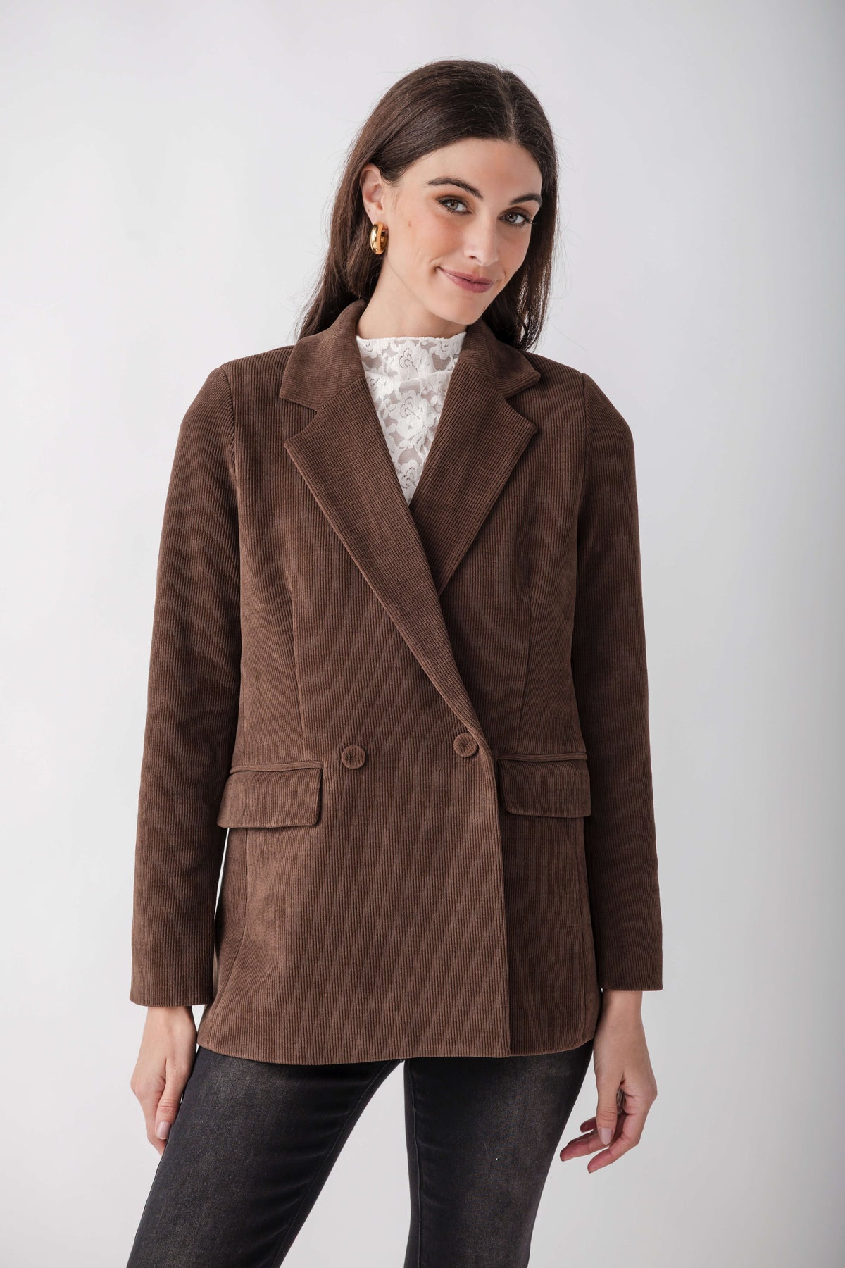Brown corduroy double-breasted blazer with notch lapels, worn over a white lace top and dark jeans.