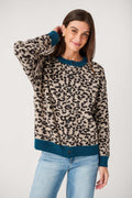 A woman wears a buttoned leopard-print knit cardigan with teal collar, cuffs and hem, styled with light blue jeans.
